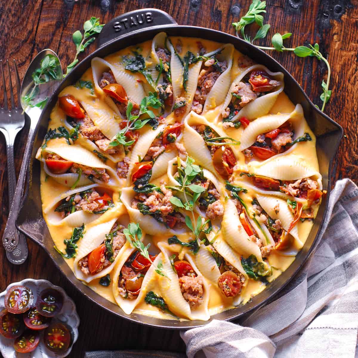 Butternut Squash Pasta Shells Stuffed with Sausage, Spinach, Tomatoes in a cast iron skillet.