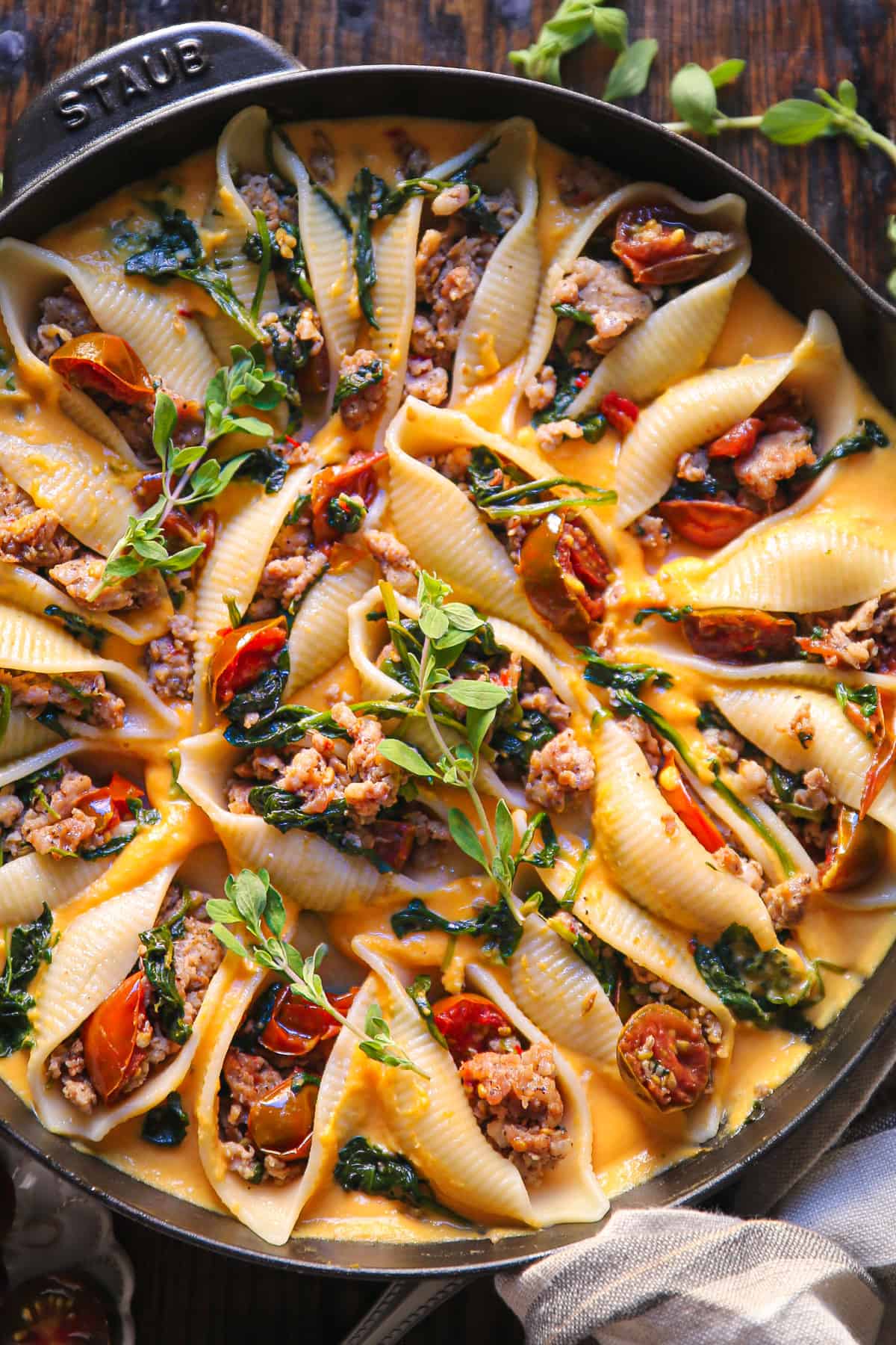 Creamy Butternut Squash Pasta Shells Stuffed with Sausage, Spinach, and Tomatoes in a cast iron skillet.