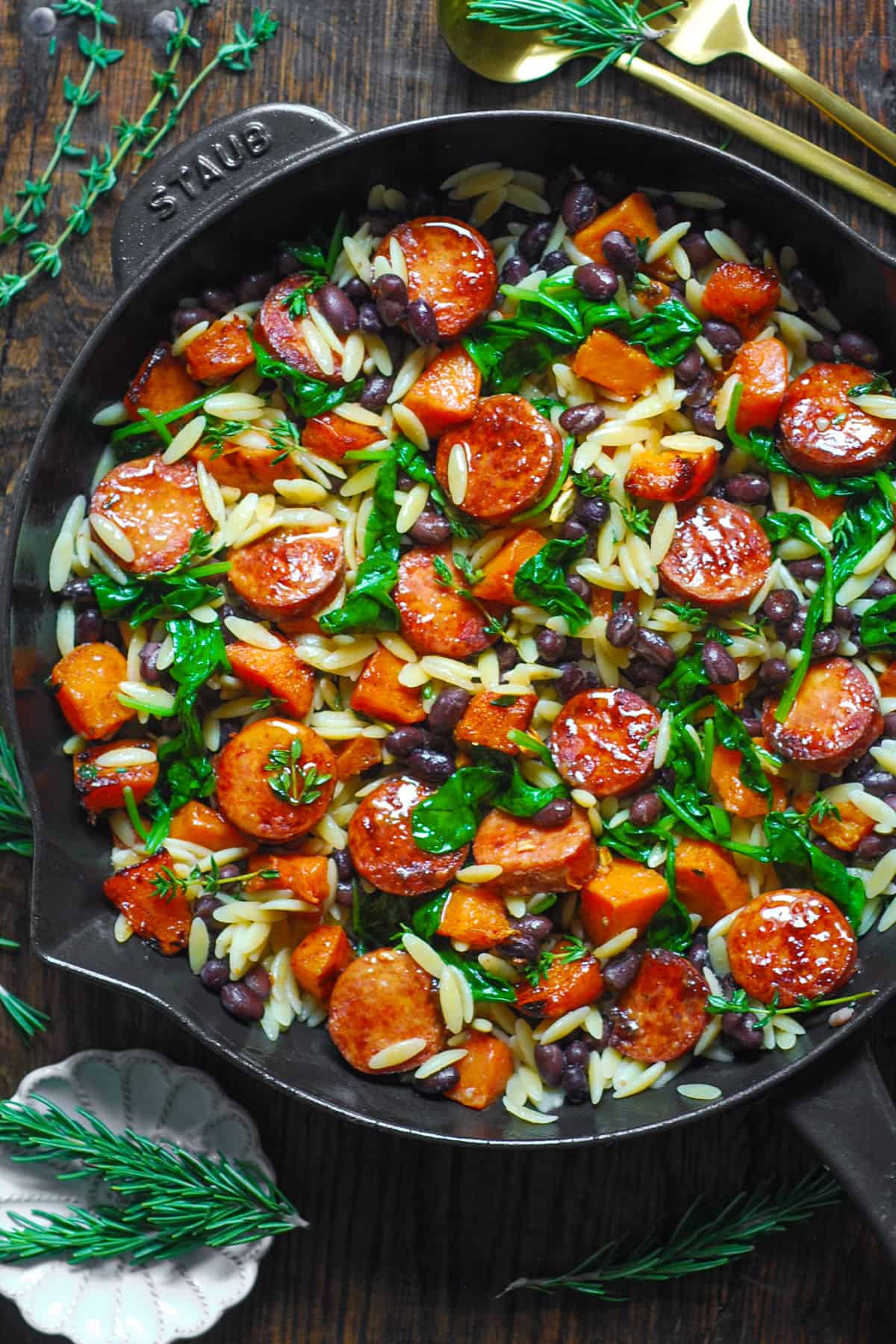 Butternut Squash and Black Bean Orzo with Sausage and Spinach in a cast iron skillet.