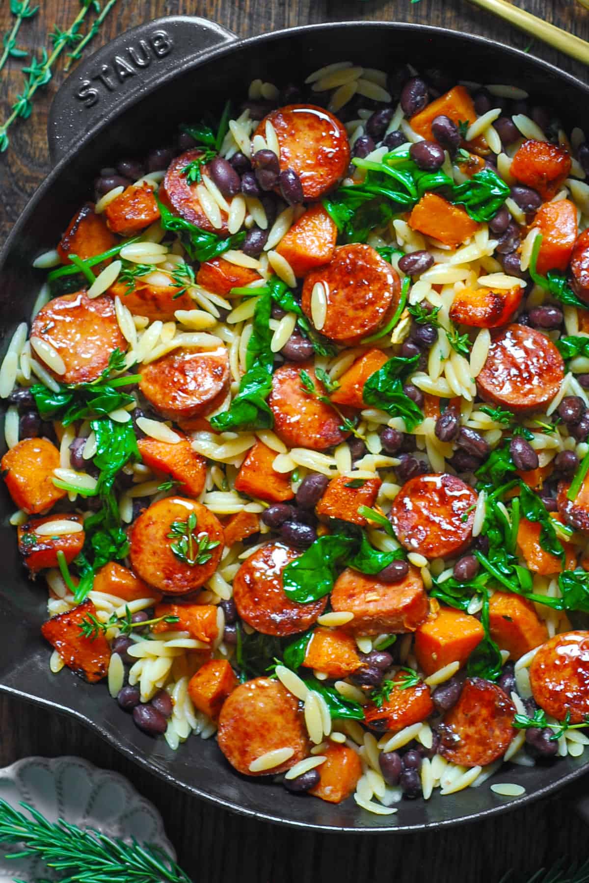 Butternut Squash and Black Bean Orzo with Sausage and Spinach in a cast iron skillet.