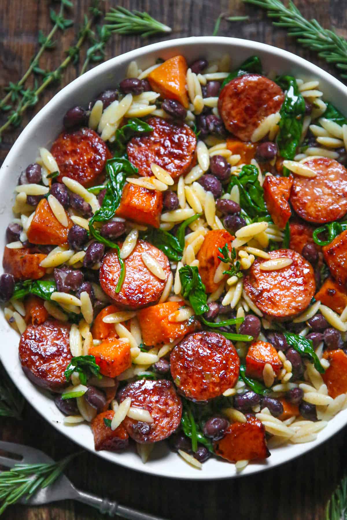 Butternut Squash and Black Bean Orzo with Sausage and Spinach in a white bowl.