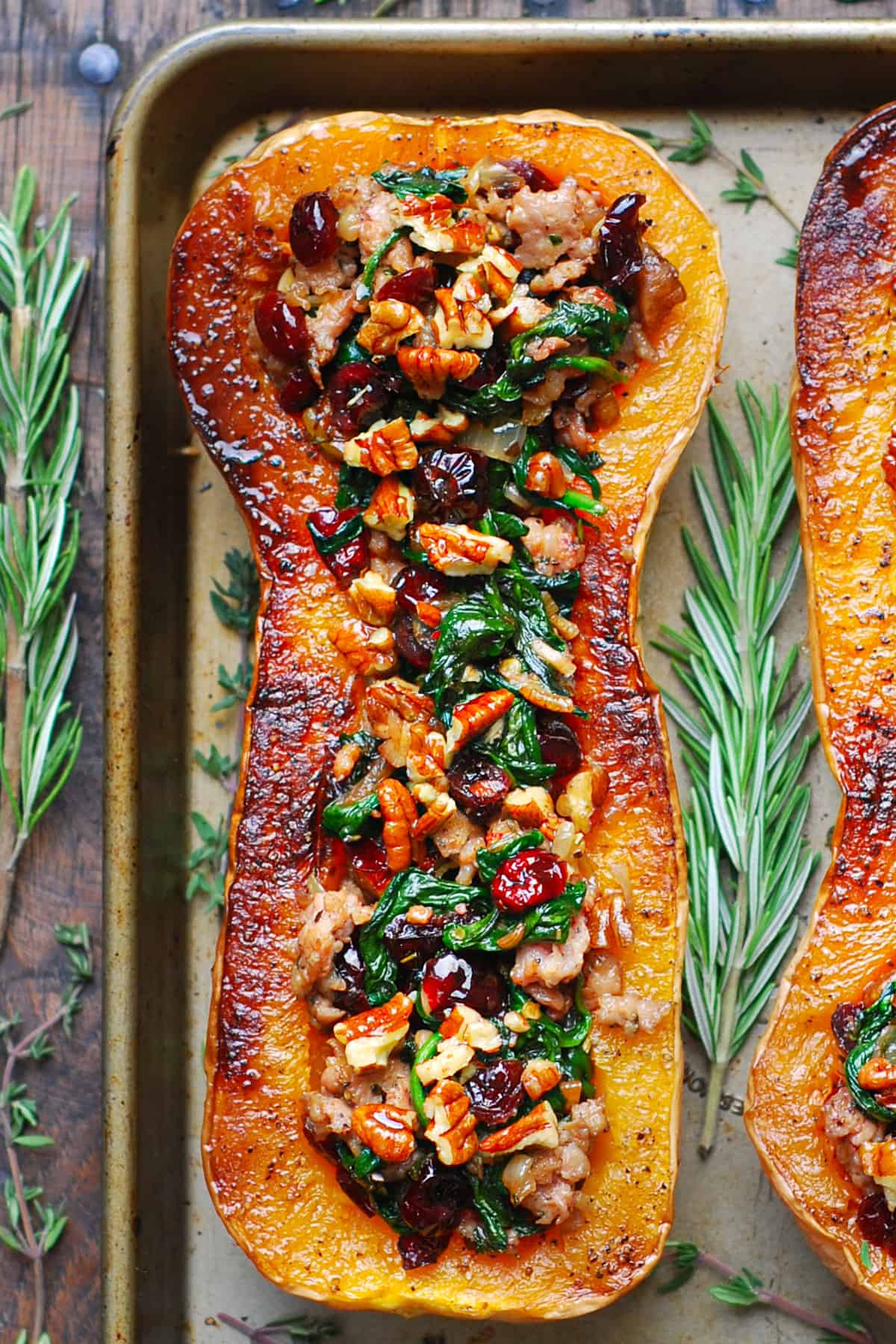Sausage Stuffed Butternut Squash with Spinach, Pecans, and Cranberries on a baking sheet.