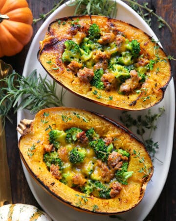 Stuffed Roasted Spaghetti Squash Halves (2) with Broccoli, Sausage, and Cheddar Cheese - on a white platter.