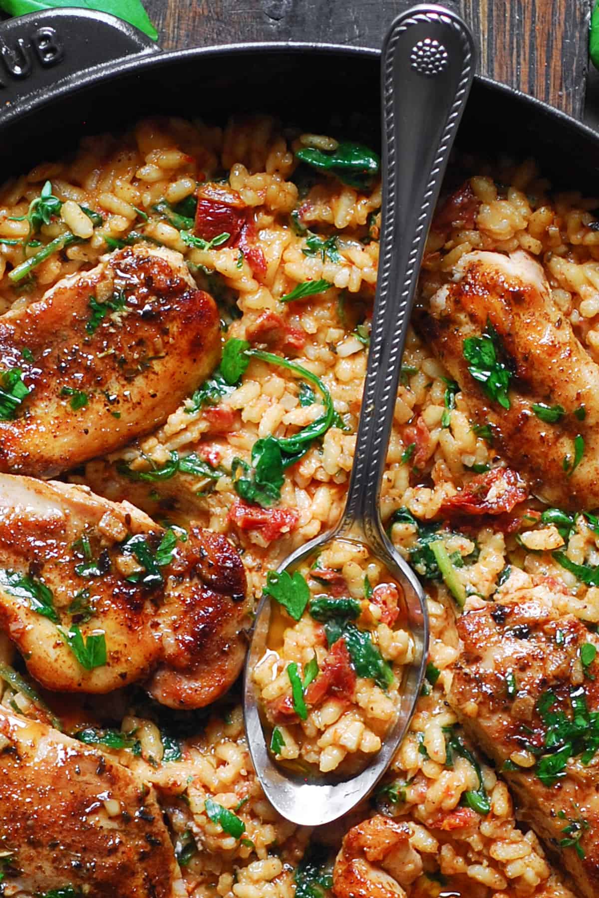 close-up photo of Chicken Risotto with Sun-Dried Tomatoes and Spinach in a cast iron skillet.