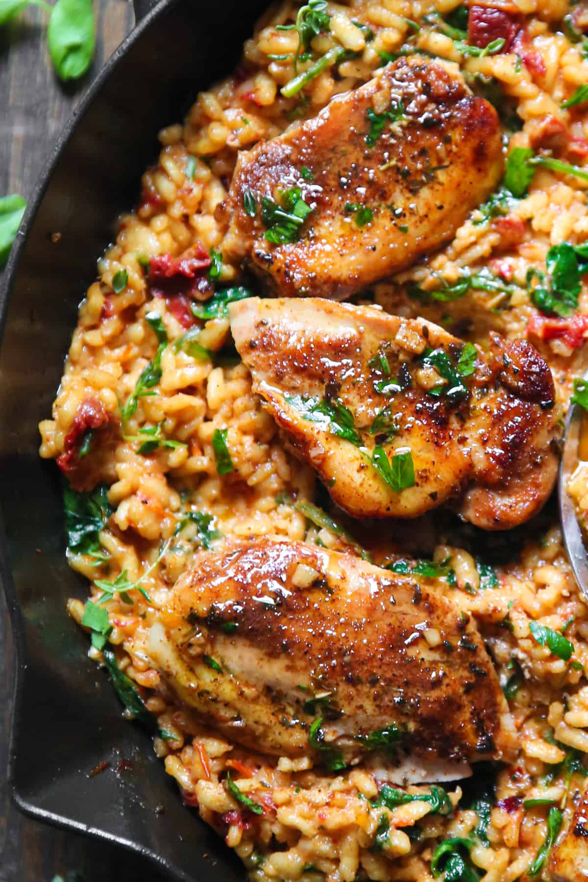 Chicken Risotto with Sun-Dried Tomatoes and Spinach in a cast iron skillet.