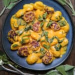 Creamy Pumpkin Gnocchi with Spinach and Sausage on a blue plate.