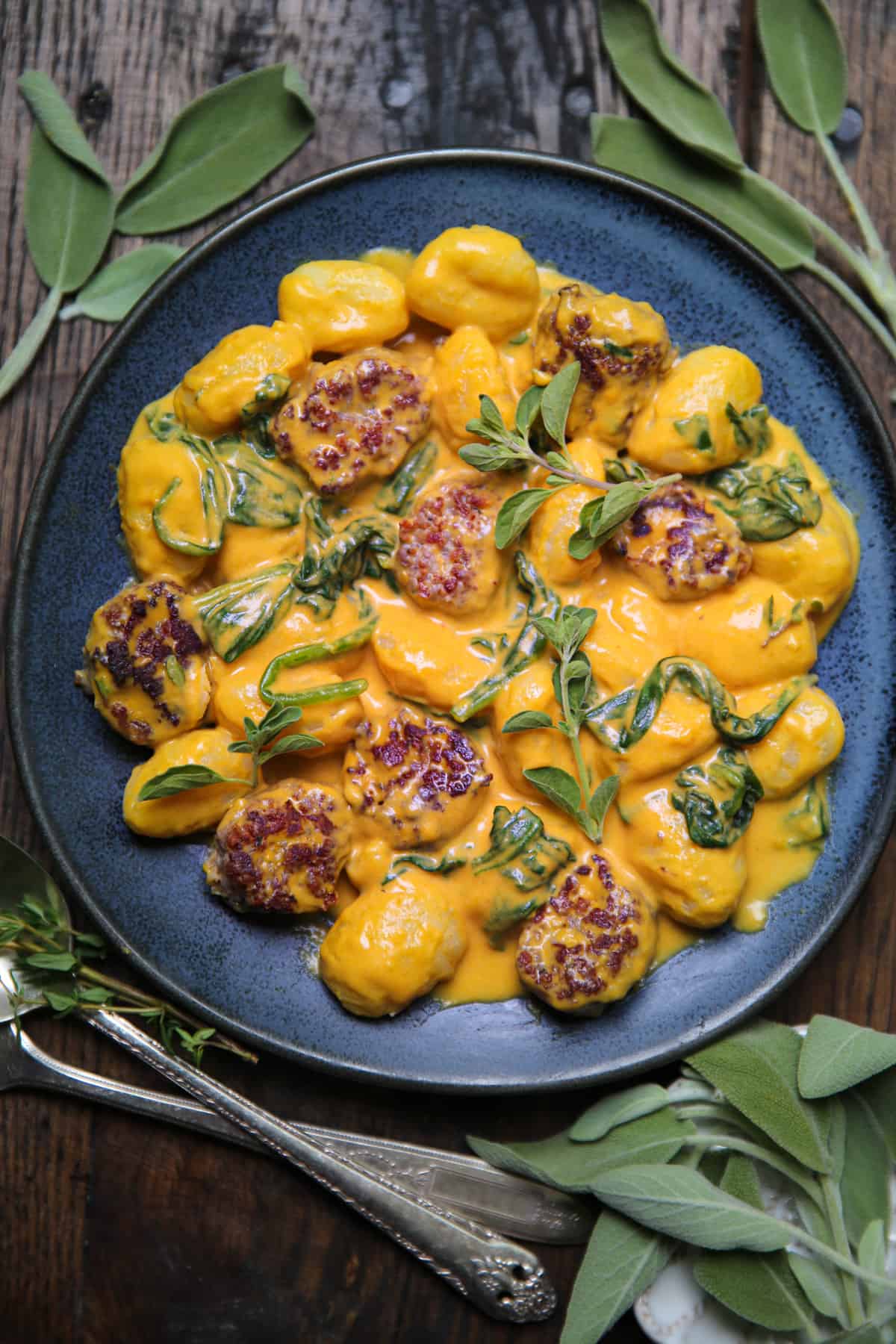 Creamy Pumpkin Gnocchi with Spinach and Sausage on a blue plate.