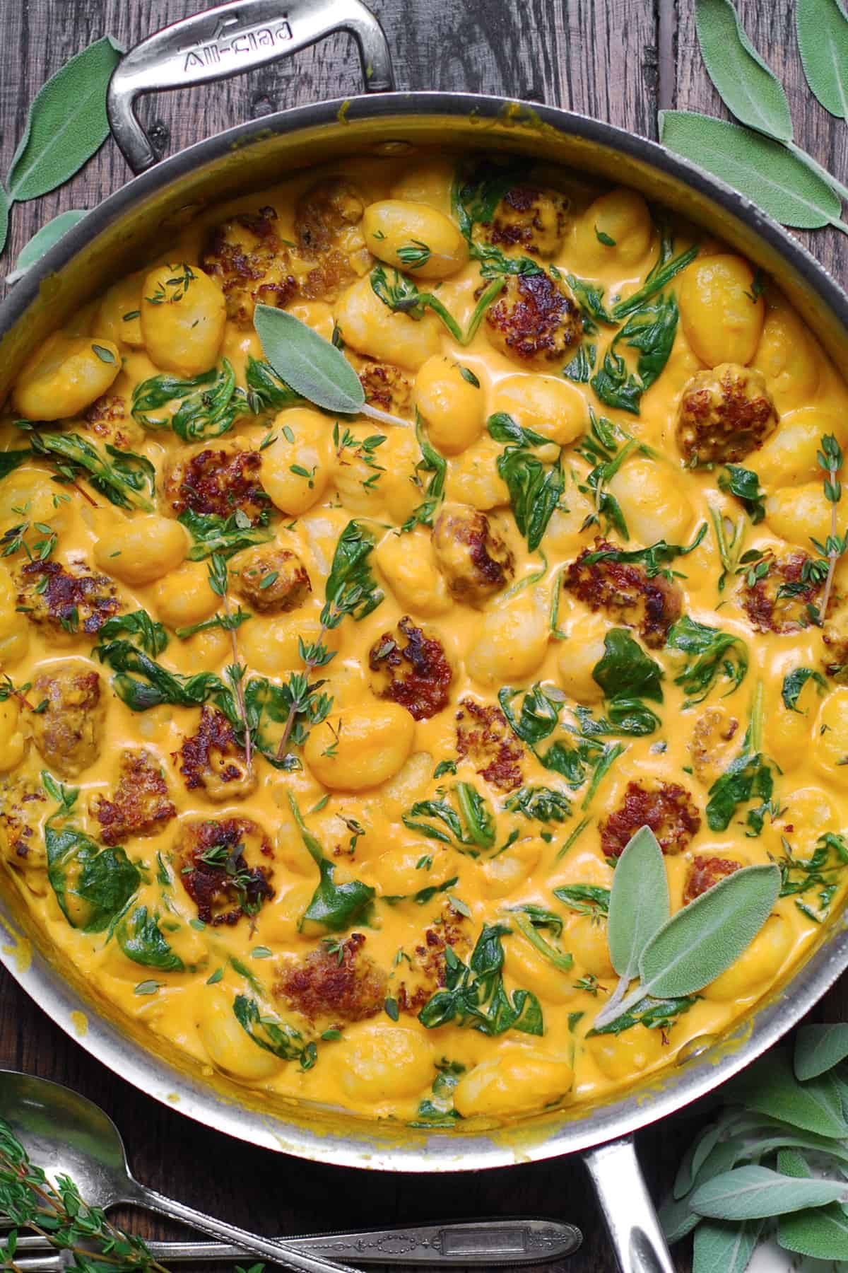 Creamy Pumpkin Gnocchi with Spinach and Sausage in a stainless steel pan.