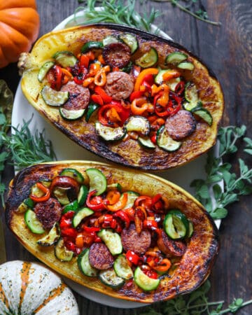 stuffed spaghetti squash (2 halves) with sausage, bell peppers, zucchini - on a white platter.