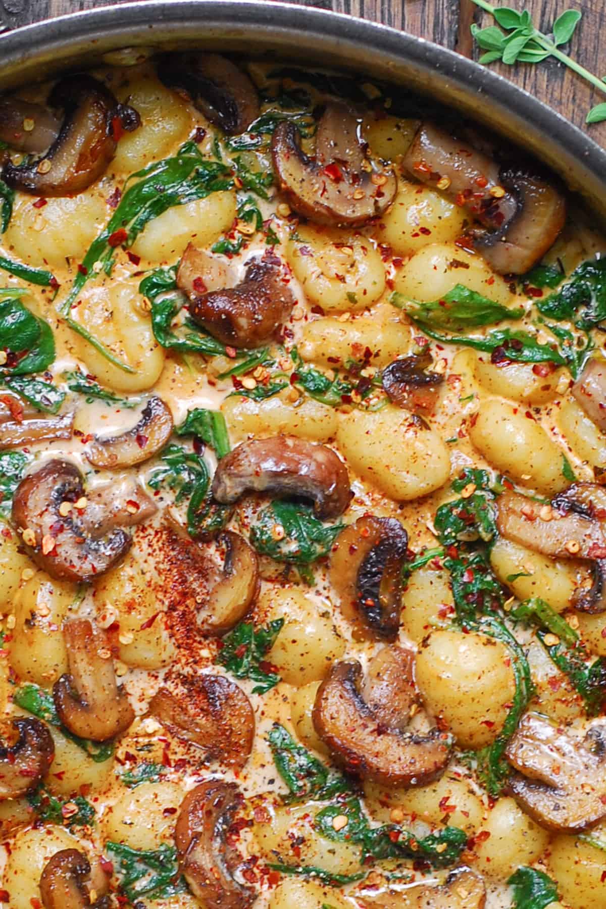 Creamy Spinach and Mushroom Gnocchi in a stainless steel pan.