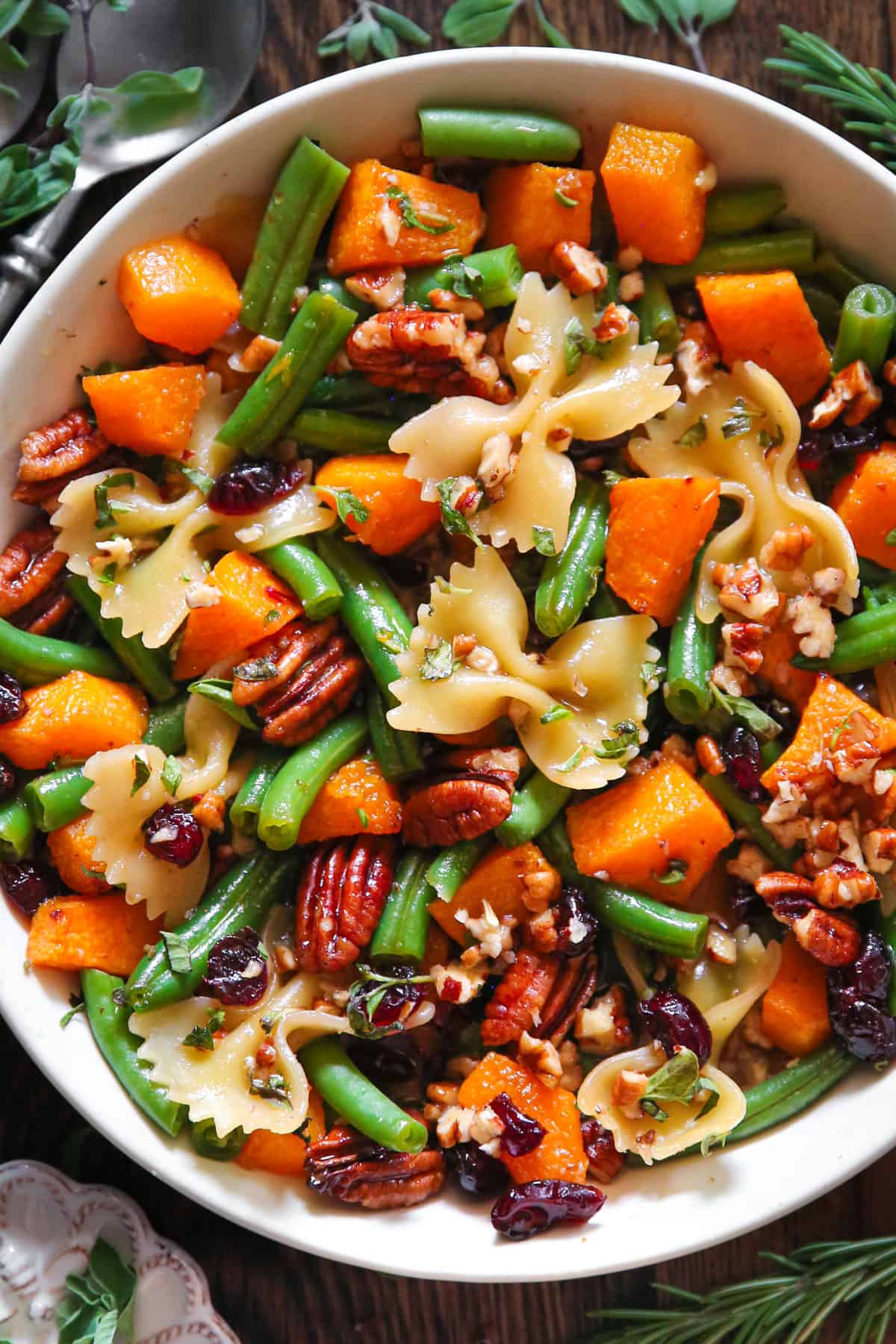 Green Bean Pasta Salad with Roasted Butternut Squash, Pecans, Bow-Tie Pasta, and Dried Cranberries - in a white bowl.