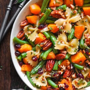 Green Bean Pasta Salad with Roasted Butternut Squash, Pecans, Bow-Tie Pasta, and Dried Cranberries - in a white bowl.