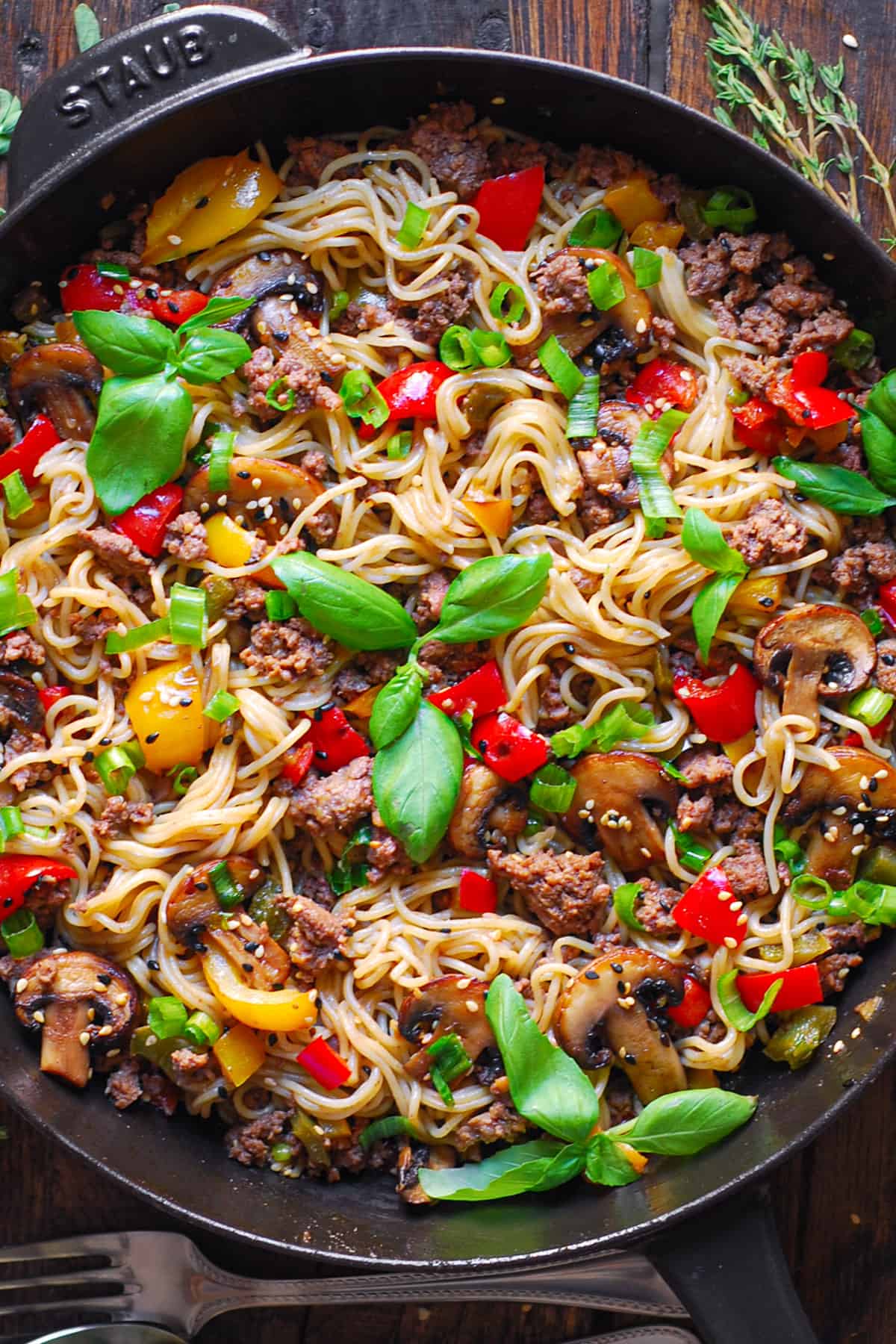 Ground Beef Ramen Noodles with Bell Peppers and Mushrooms in a cast iron pan.