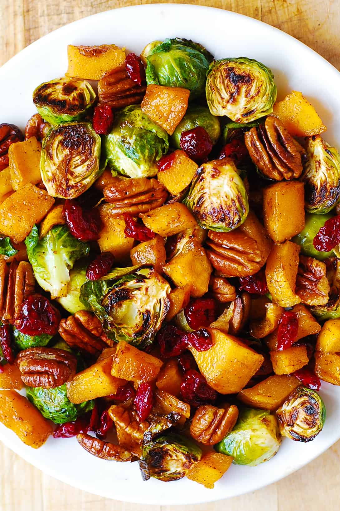 Roasted Brussels sprouts and Cinnamon Butternut Squash with Pecans and Dried Cranberries - on a white plate.