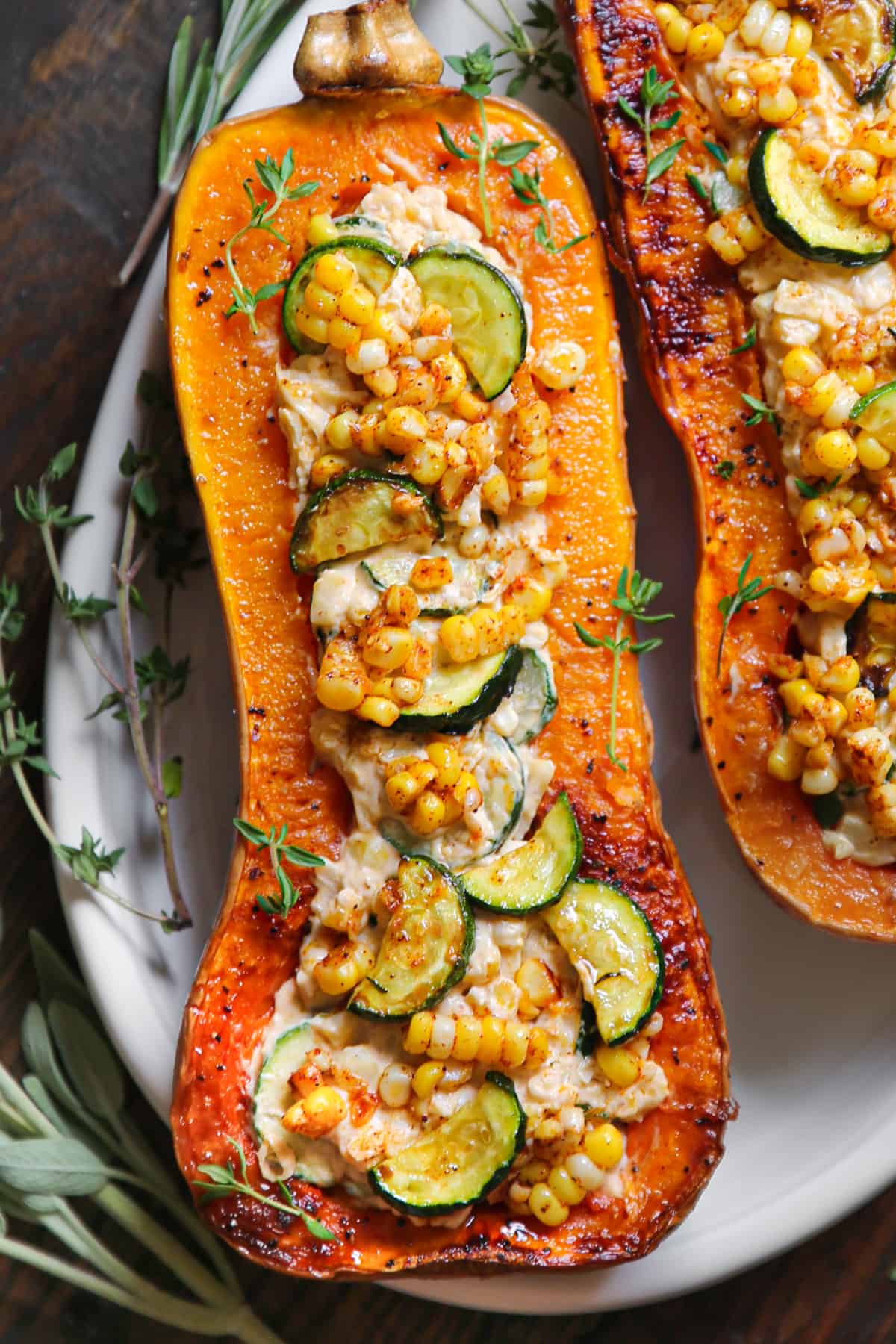 Roasted Butternut Squash Half stuffed with Corn, Zucchini, and Cheese - on a white platter.