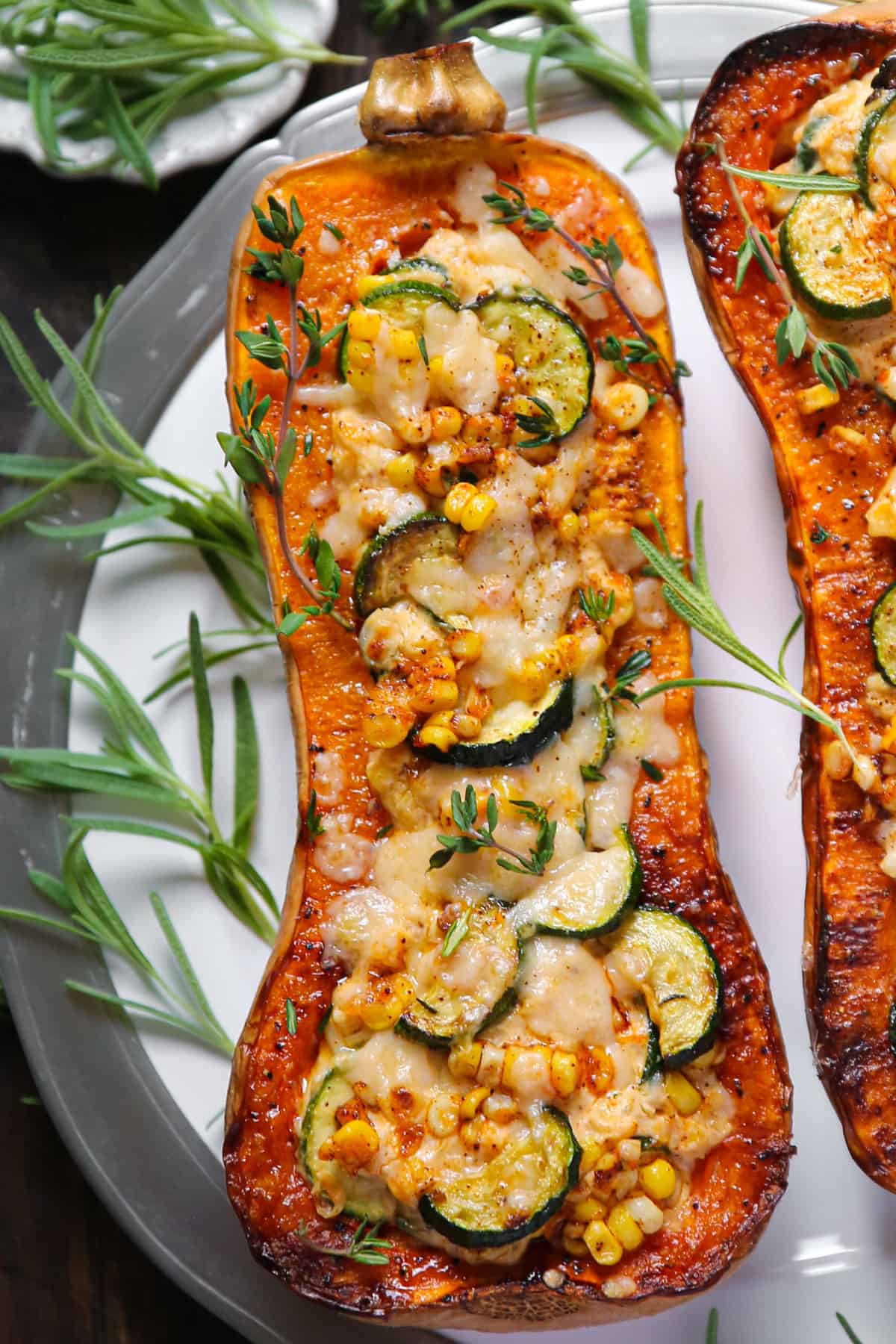 Roasted Butternut Squash Half stuffed with Corn, Zucchini, and Cheese - on a white plate.