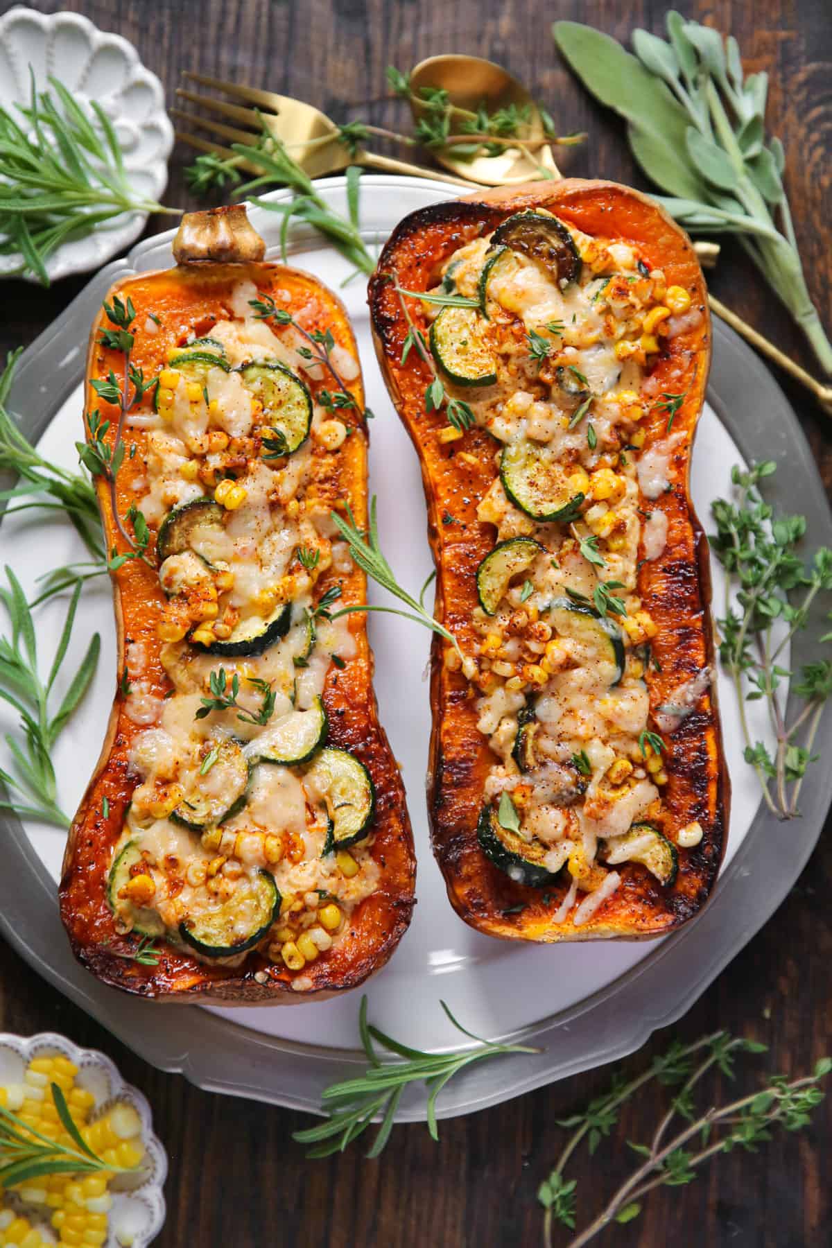 Roasted Butternut Squash (2 halves) stuffed with Corn, Zucchini, and Cheese - on a white plate.