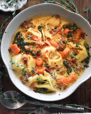 Creamy Italian Sausage Tortellini Soup with Spinach and Carrots in a white bowl.
