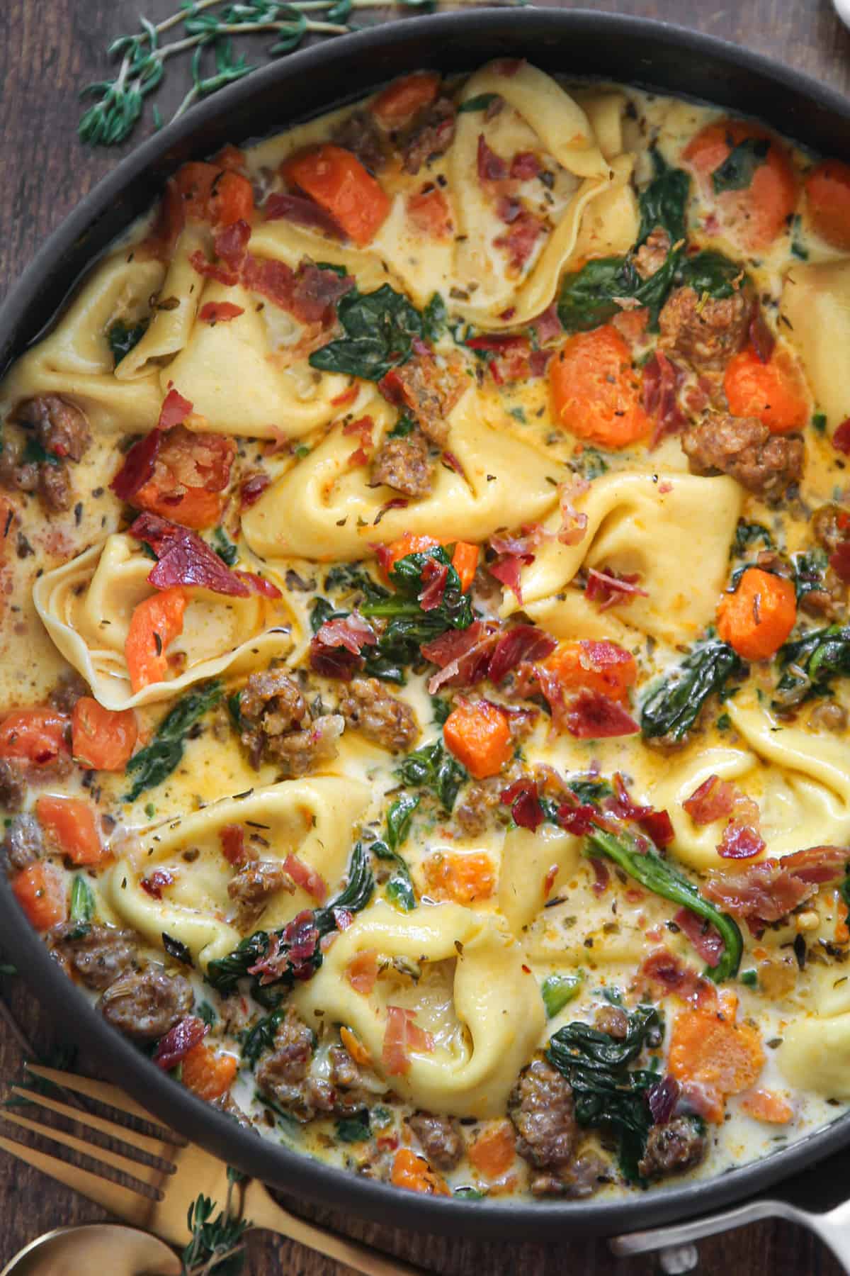 Creamy Italian Sausage Tortellini Soup with Spinach and Carrots in a saucepan.