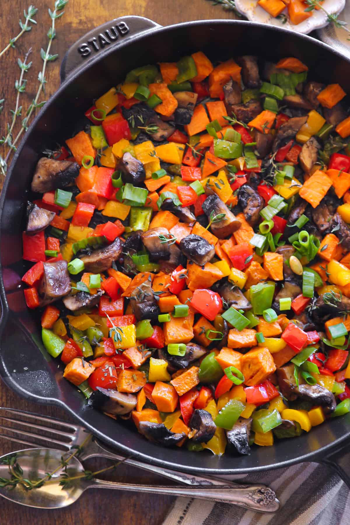 Sweet Potato Hash with Bell Peppers, Portobello Mushrooms, Green Onions, and Garlic in a cast iron skillet.