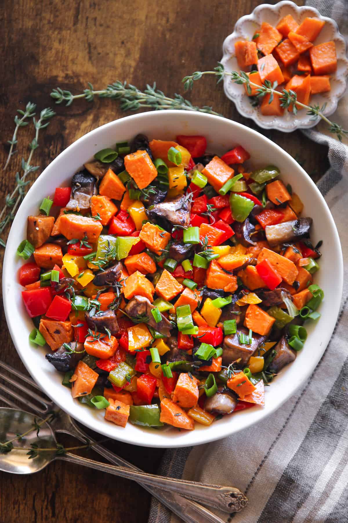 Sweet Potato Hash with Bell Peppers, Portobello Mushrooms, Green Onions, and Garlic in a white bowl.