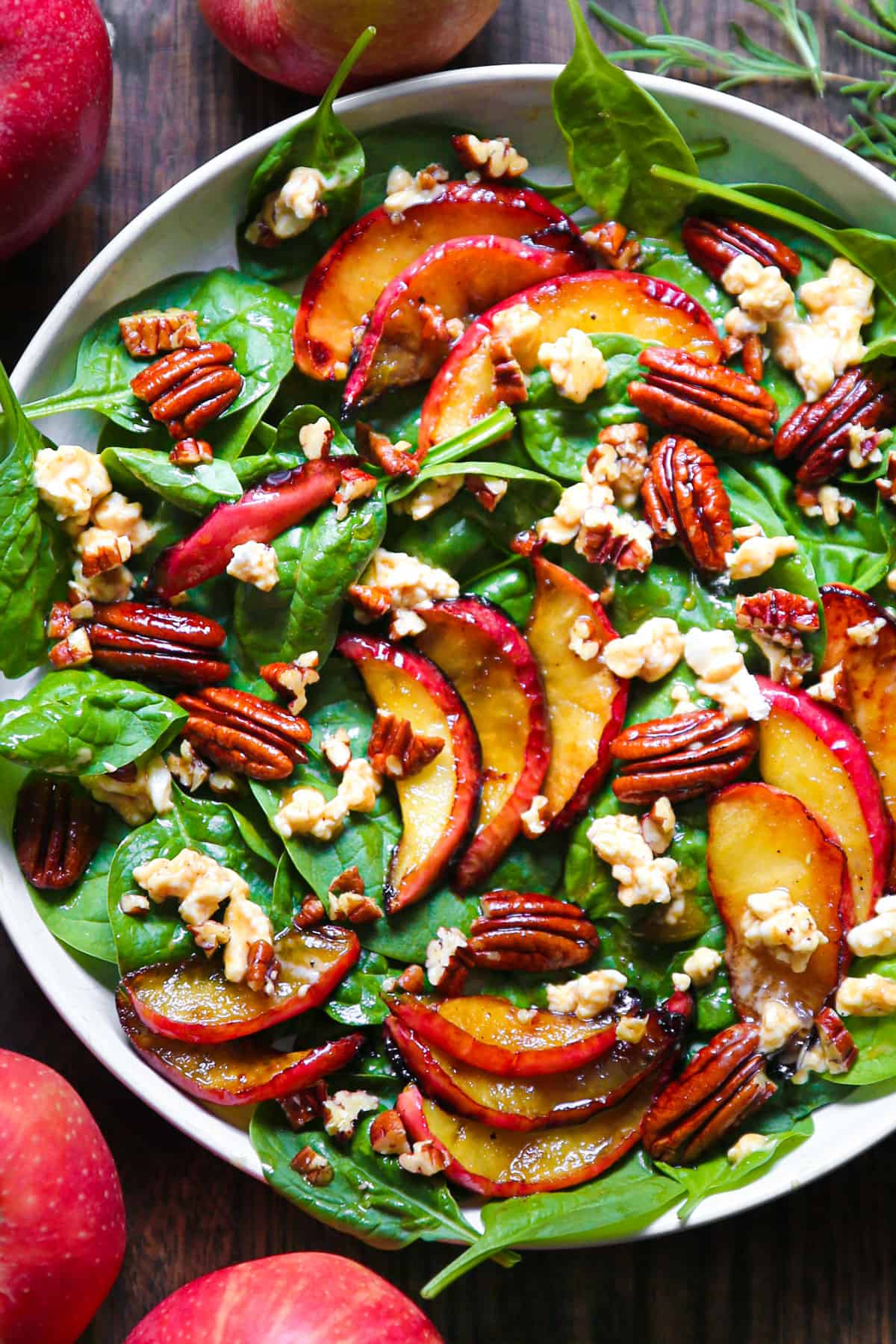 Fall Harvest Salad with Cooked Apples, Pecans, Spinach, and Maple-Lime Dressing - in a white bowl.