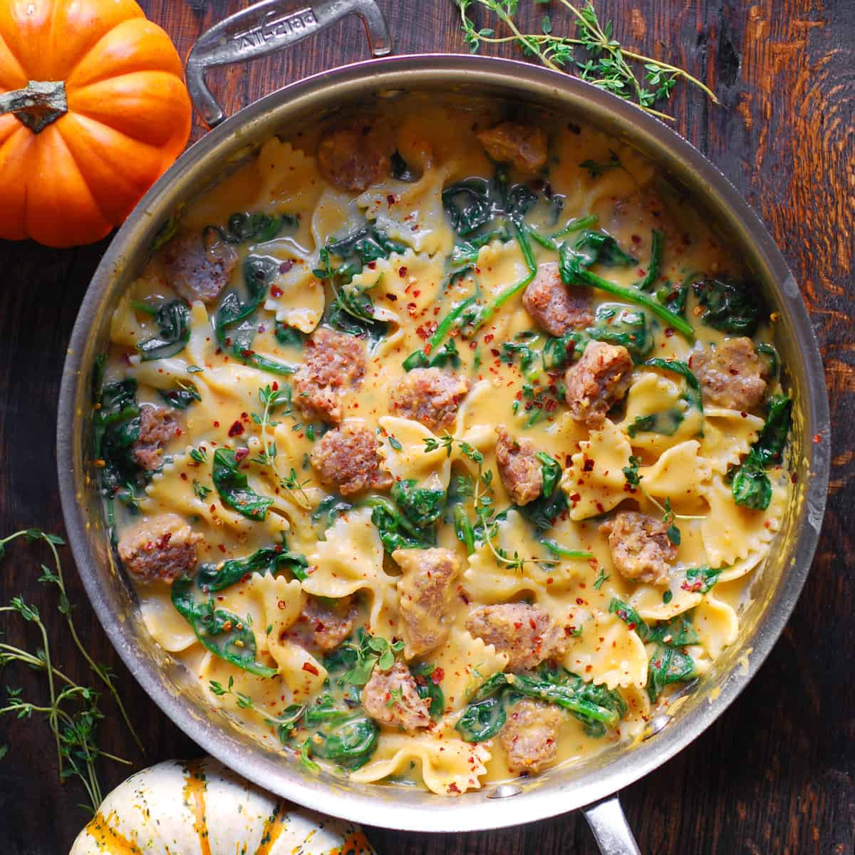 butternut squash bow-tie pasta with Italian sausage and spinach - in a stainless steel pan.