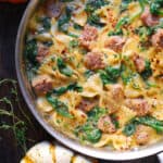 butternut squash bow-tie pasta with Italian sausage and spinach - in a stainless steel pan.