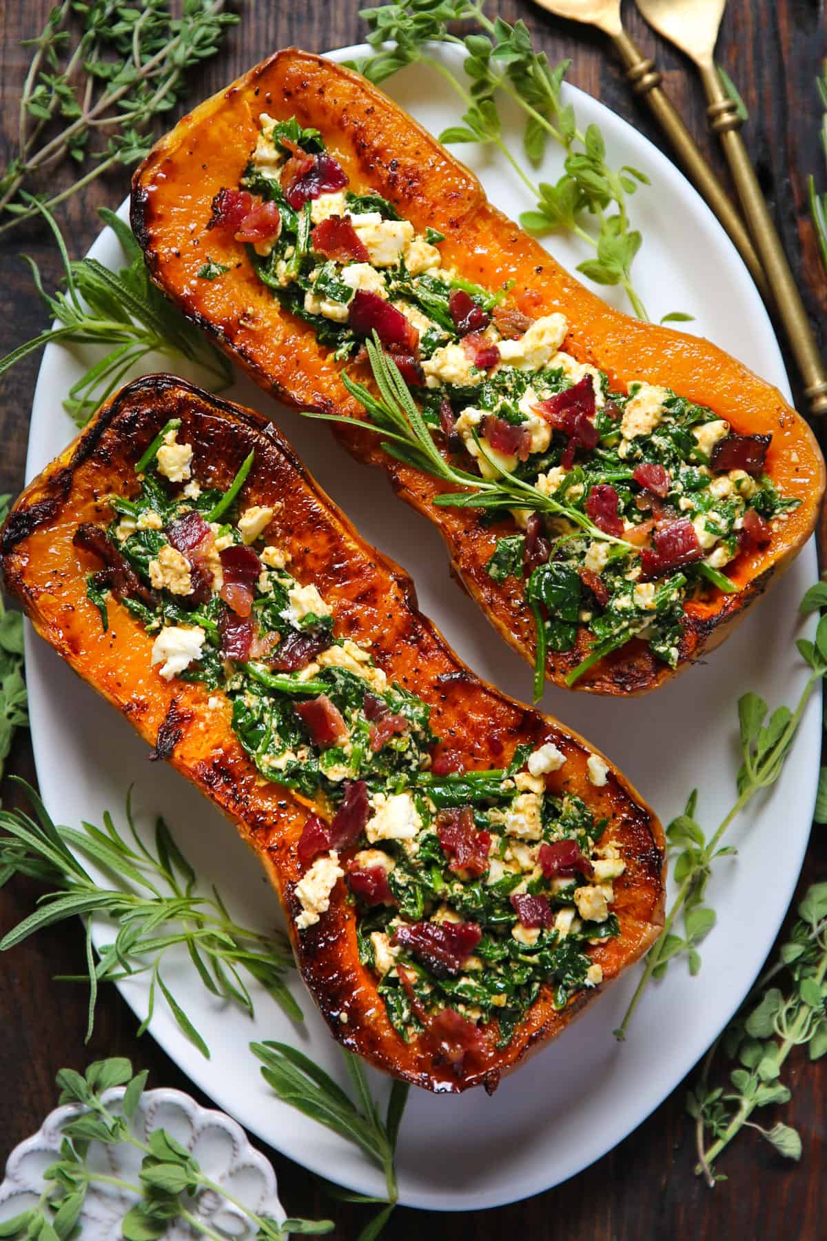 Stuffed Roasted Butternut Squash (2 halves) with Feta Cheese, Spinach, and Bacon - on a white platter.