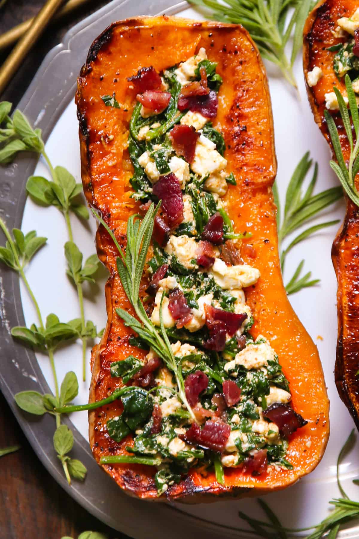 Stuffed Roasted Butternut Squash Half with Feta Cheese, Spinach, and Bacon - on a white plate.