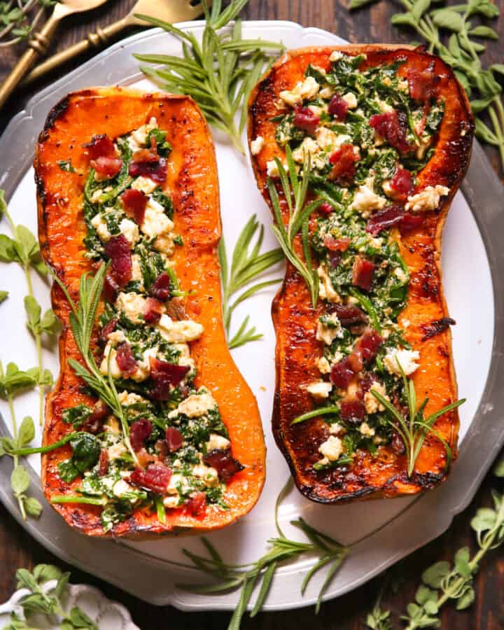 Stuffed Roasted Butternut Squash (2 halves) with Feta Cheese, Spinach, and Bacon - on a white plate.