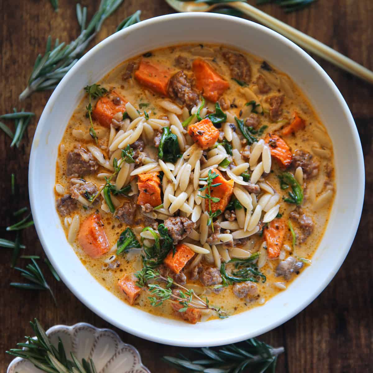 Creamy Butternut Squash and Sausage Soup with Orzo and Spinach in a white bowl.