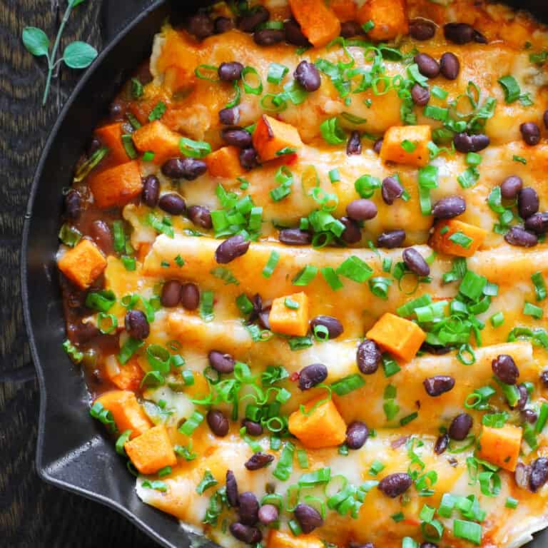 Vegetarian Enchiladas with Butternut Squash and Black Beans in a cast iron pan.