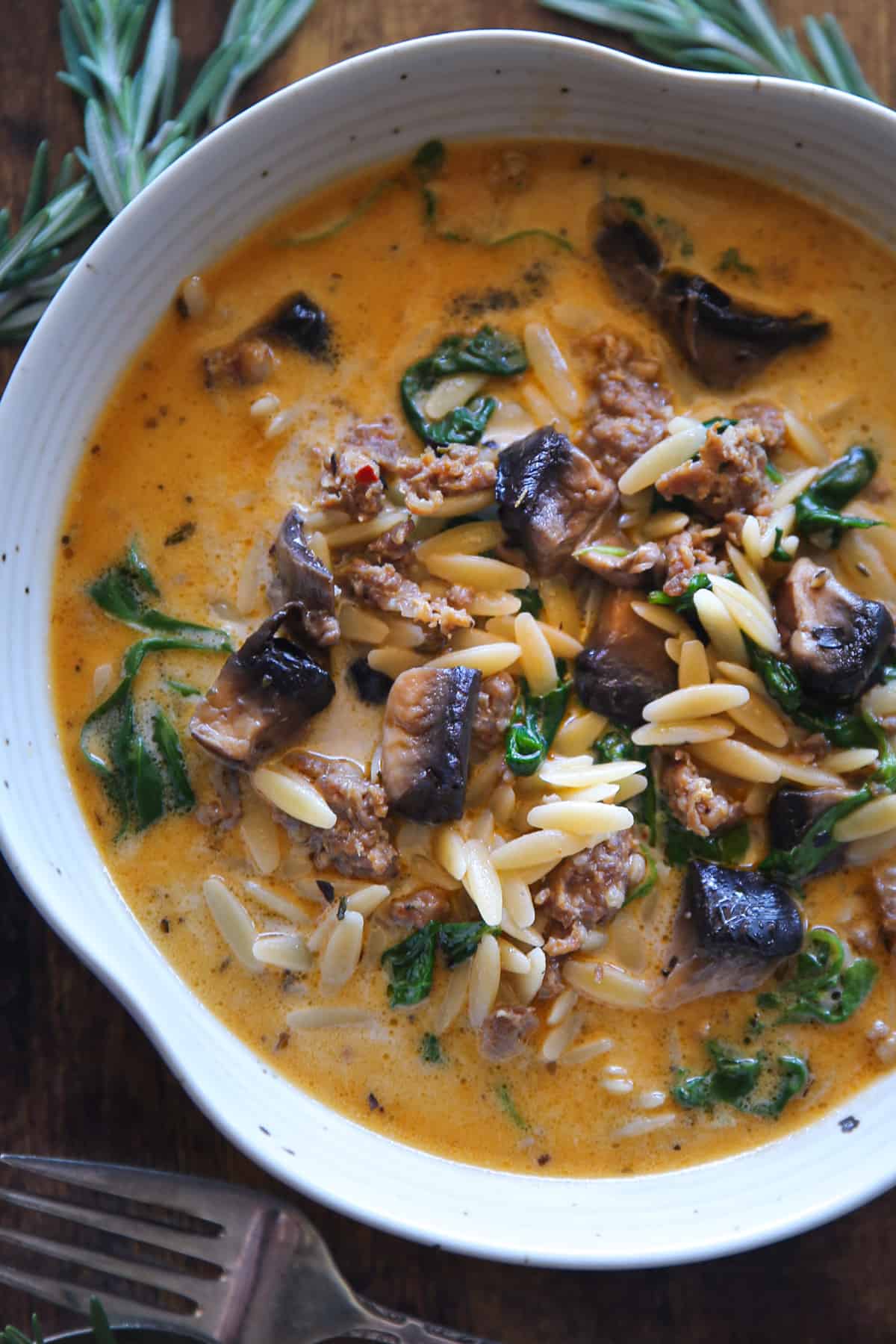 Sausage Orzo Soup with Spinach and Mushrooms in a white bowl.
