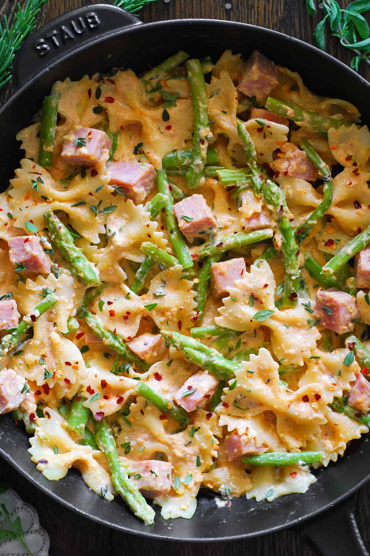 Creamy ham pasta with asparagus in a cast iron skillet.