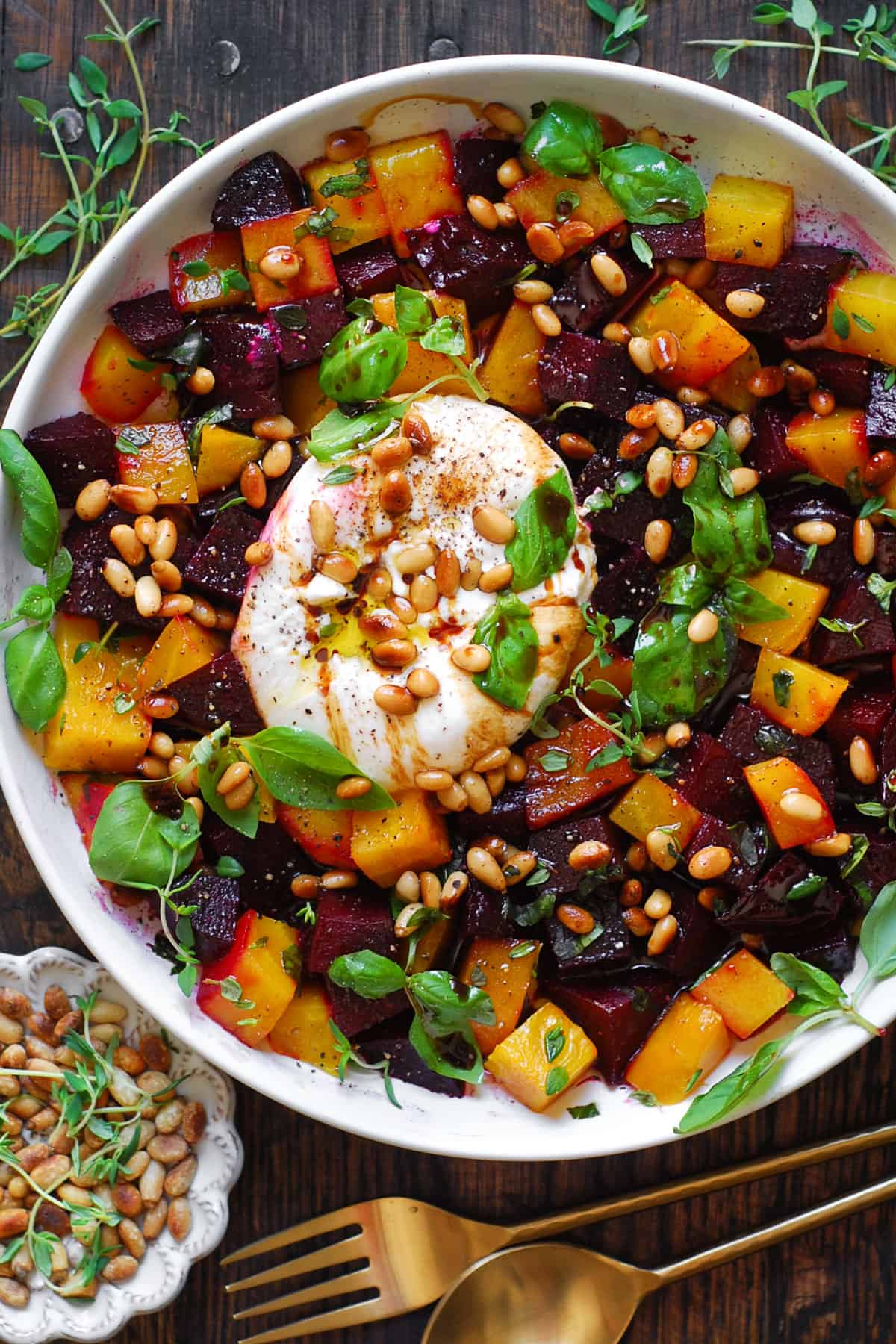 Beet and Burrata Salad with Pine Nuts, Fresh Basil, and Balsamic Dressing - on a white plate.