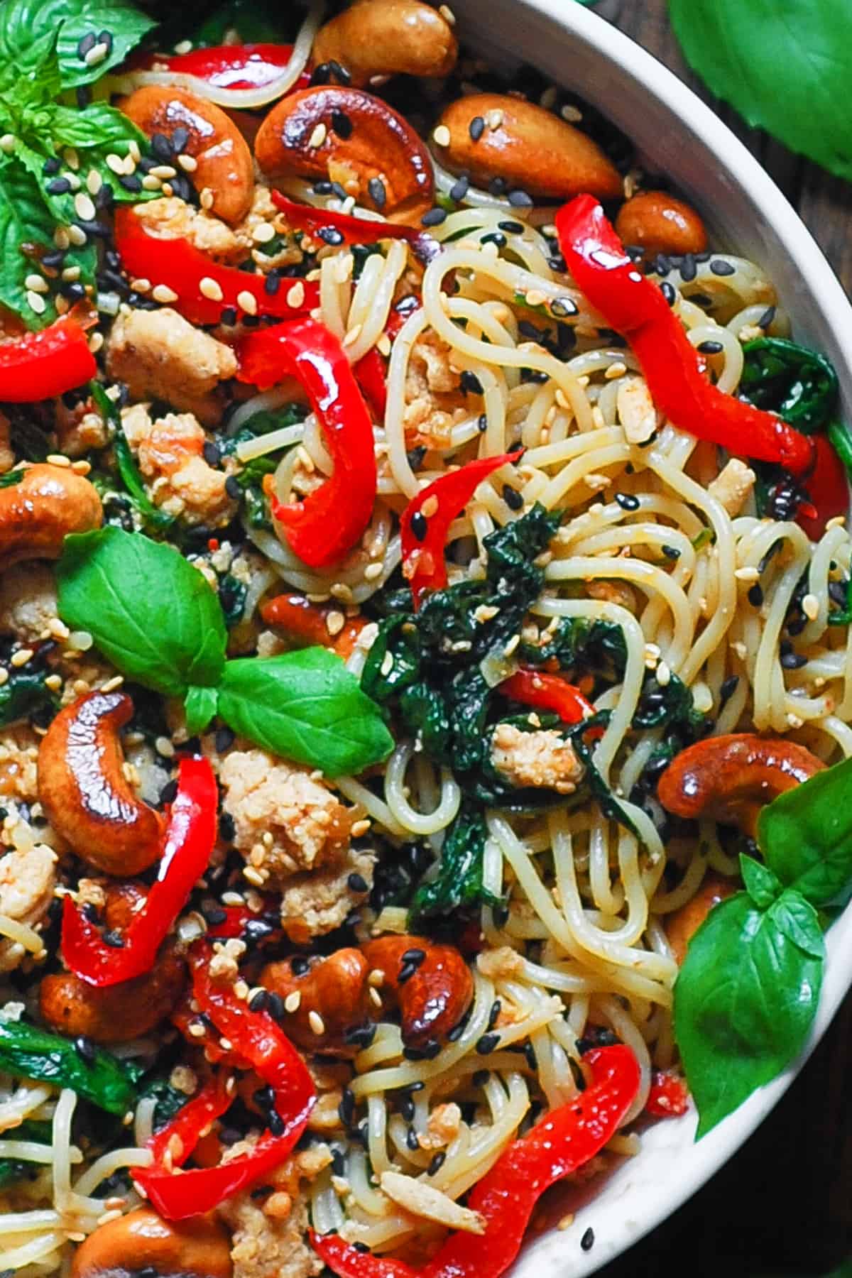 Chicken Ramen Noodles with Bell Peppers, Spinach, Cashews, and Sesame Seeds - in a white bowl.