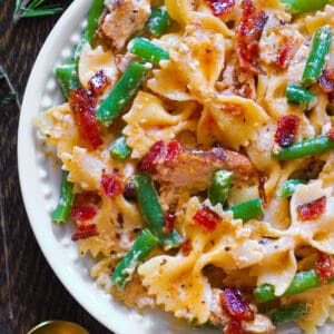 Creamy Chicken Pasta with Green Beans and Bacon on a white plate.