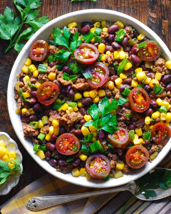 Mexican Ground Beef with Tomatoes, Corn, Black Beans, Green Onions, Green Chiles in a white bowl.