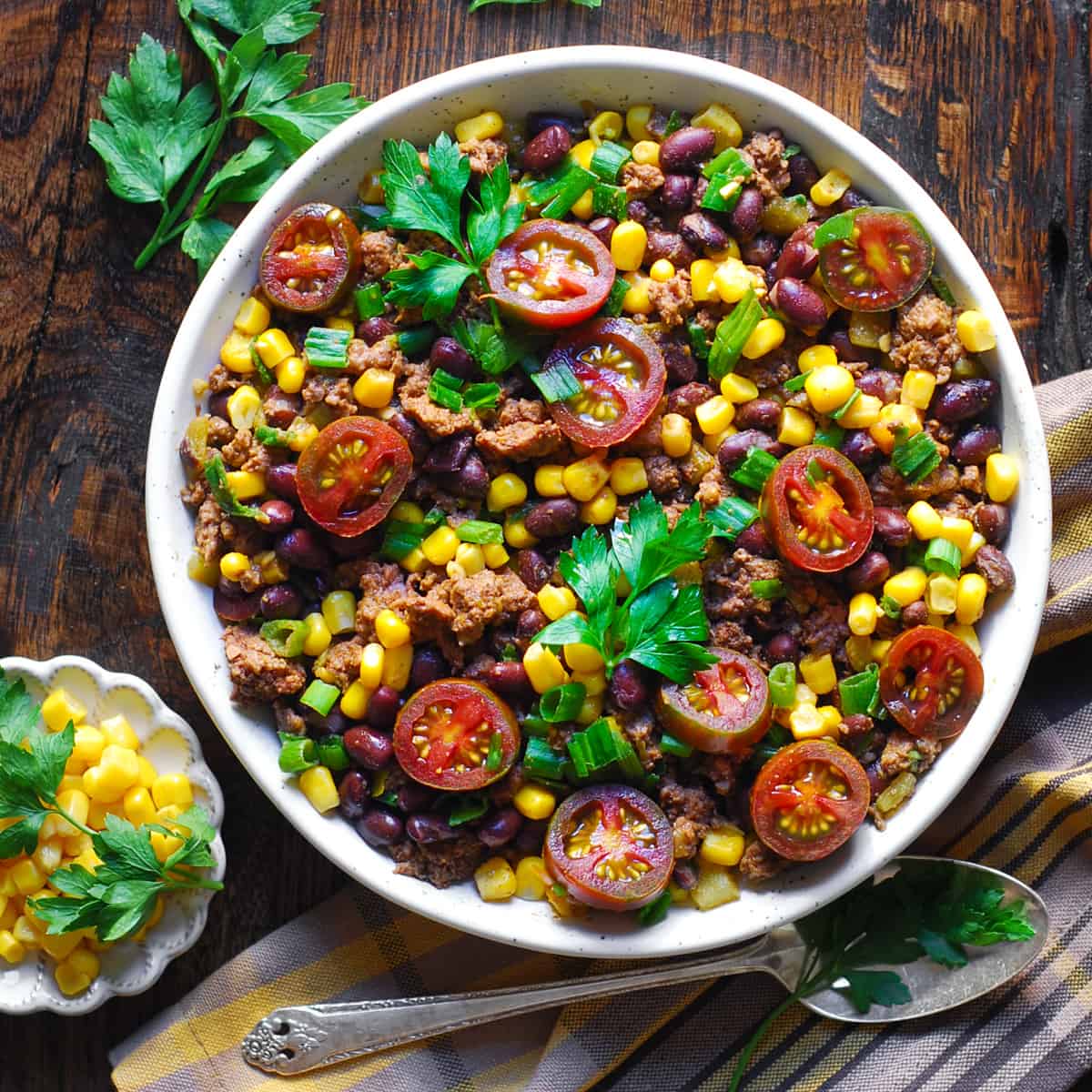 Mexican Ground Beef with Tomatoes, Corn, Black Beans, Green Onions, Green Chiles in a white bowl.