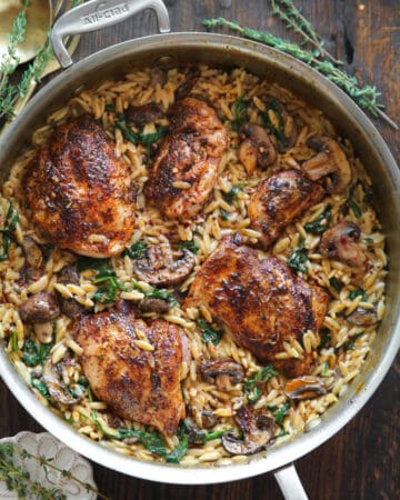 creamy chicken orzo with mushrooms and spinach - in a stainless steel pan.
