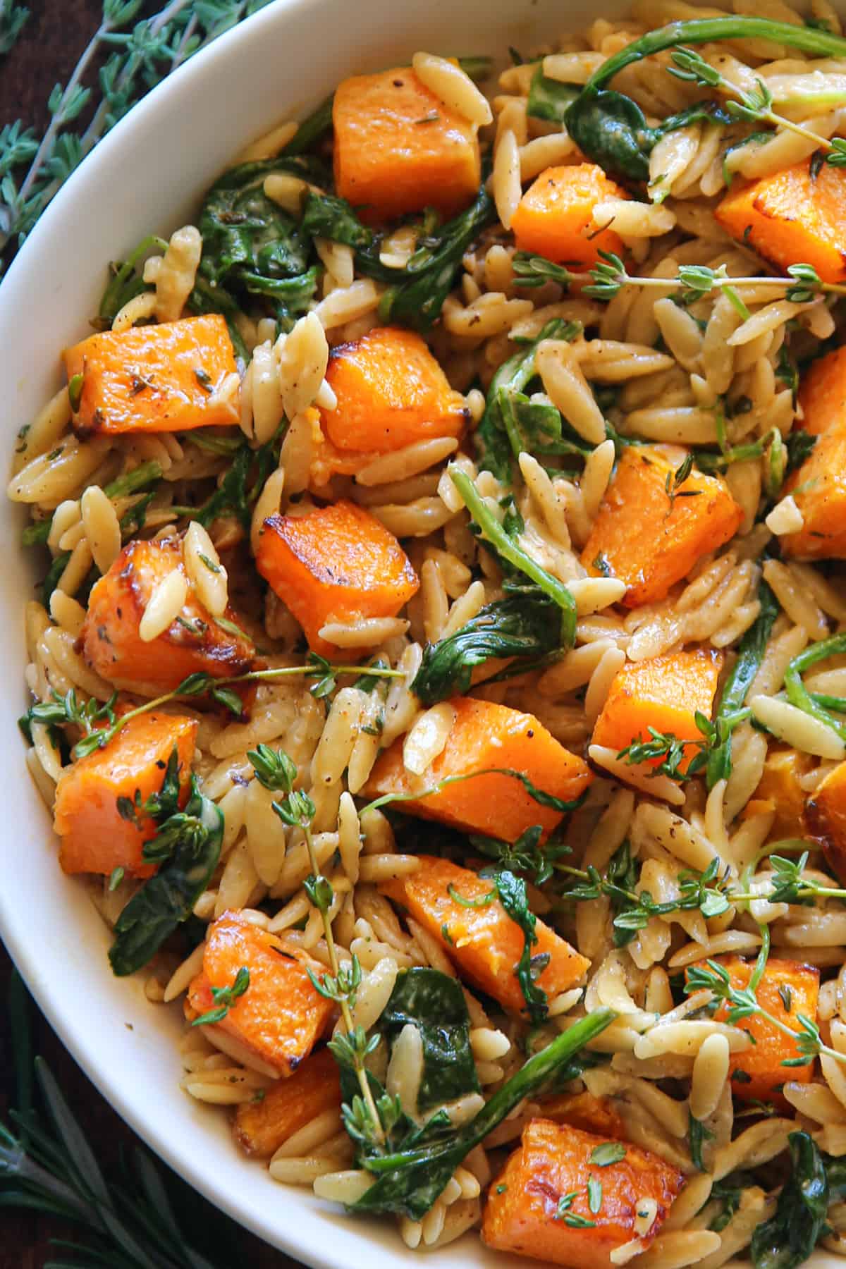 creamy orzo pasta with butternut squash and spinach in a white bowl.