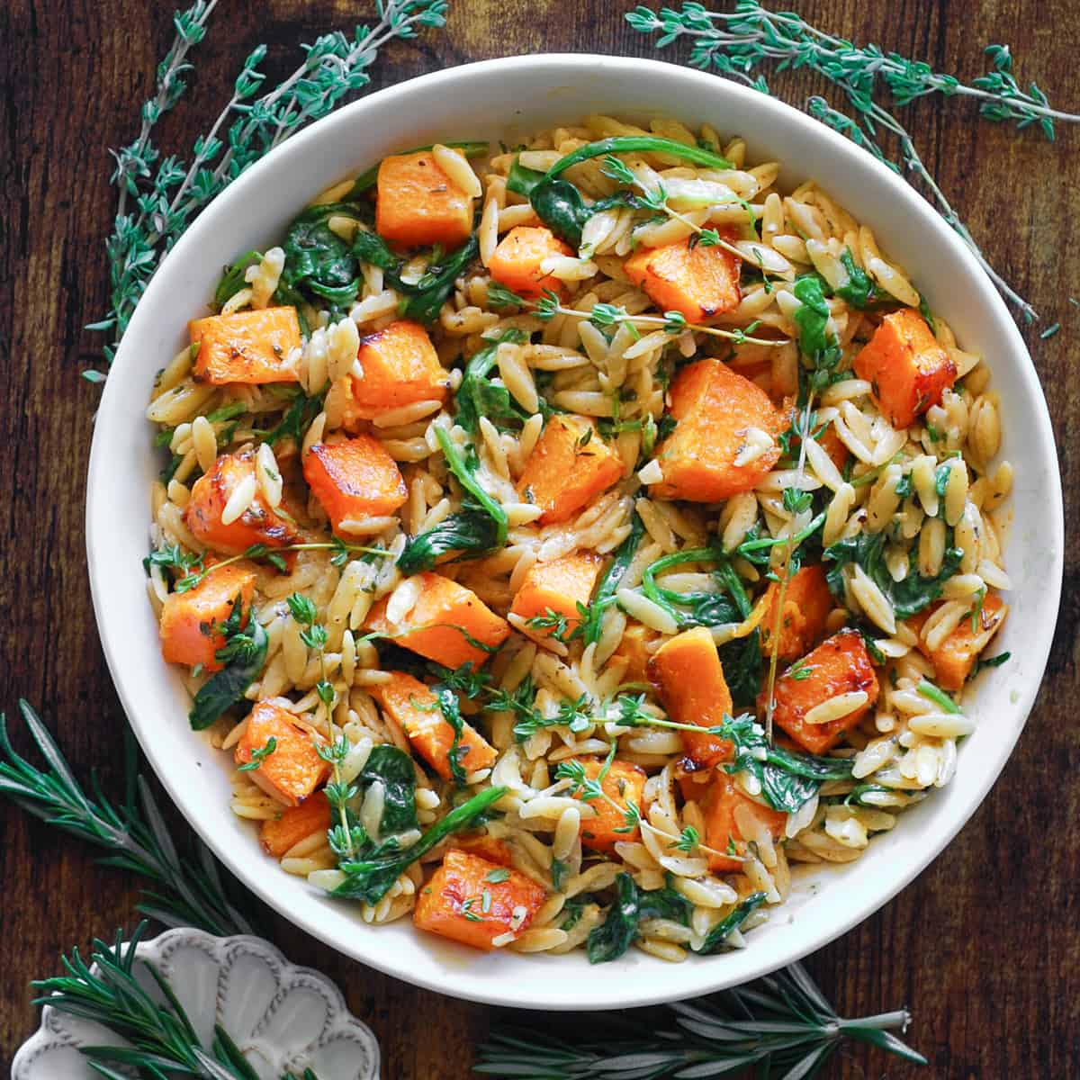 creamy orzo pasta with butternut squash and spinach in a white bowl.