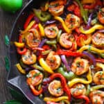 shrimp fajiitas with bell peppers and red onions - in a cast iron skillet.