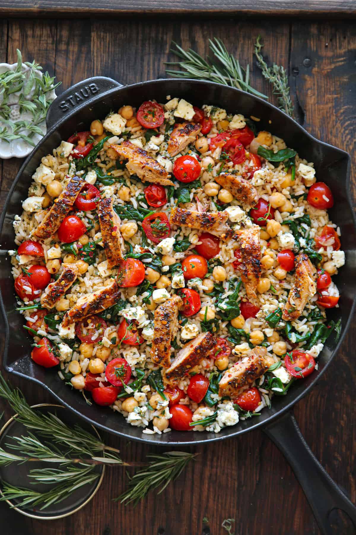 Greek Chicken and Lemon Rice with spinach, grape tomatoes, chickpeas, and feta cheese - in a cast iron skillet.