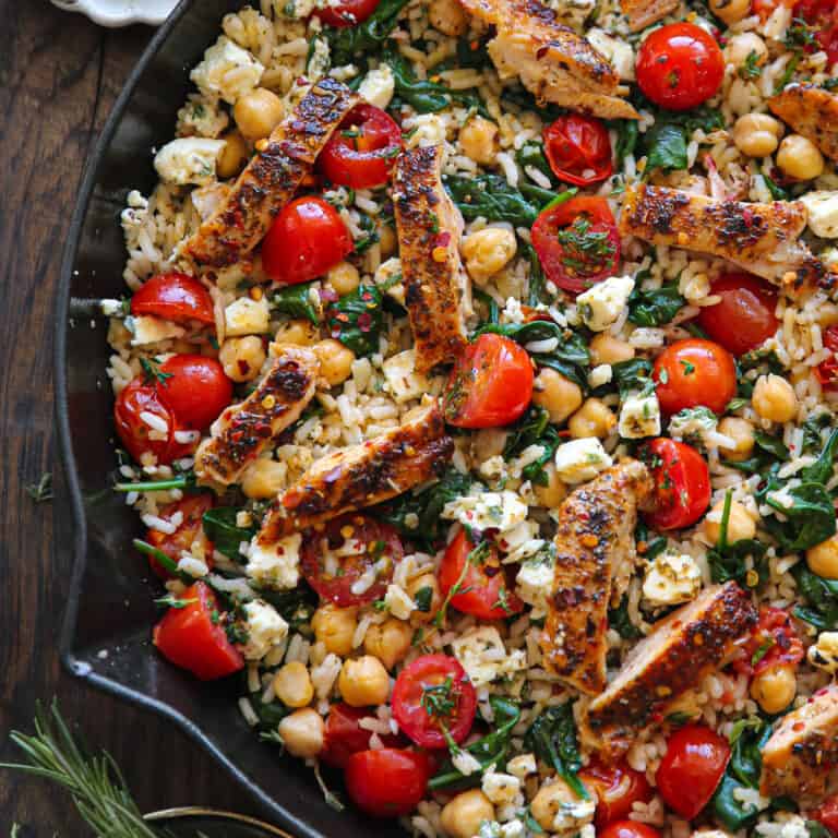 Greek Chicken and Lemon Rice with spinach, grape tomatoes, chickpeas, and feta cheese - in a cast iron skillet.