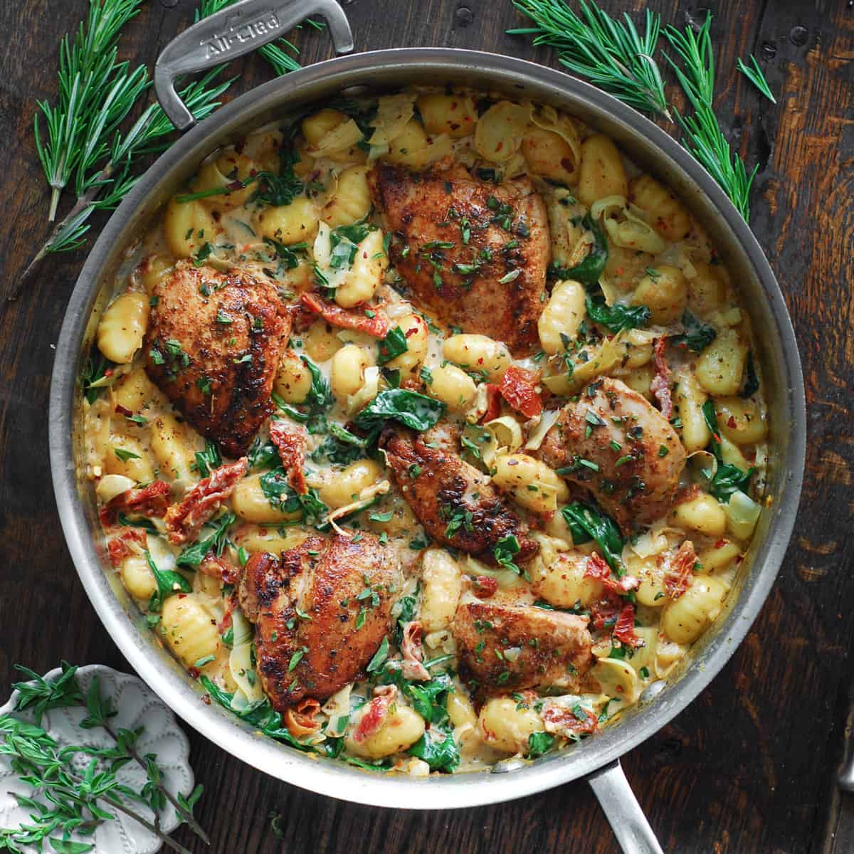 Creamy Chicken and Gnocchi with Sun-Dried Tomatoes, Spinach, and Artichokes - in a stainless steel pan.