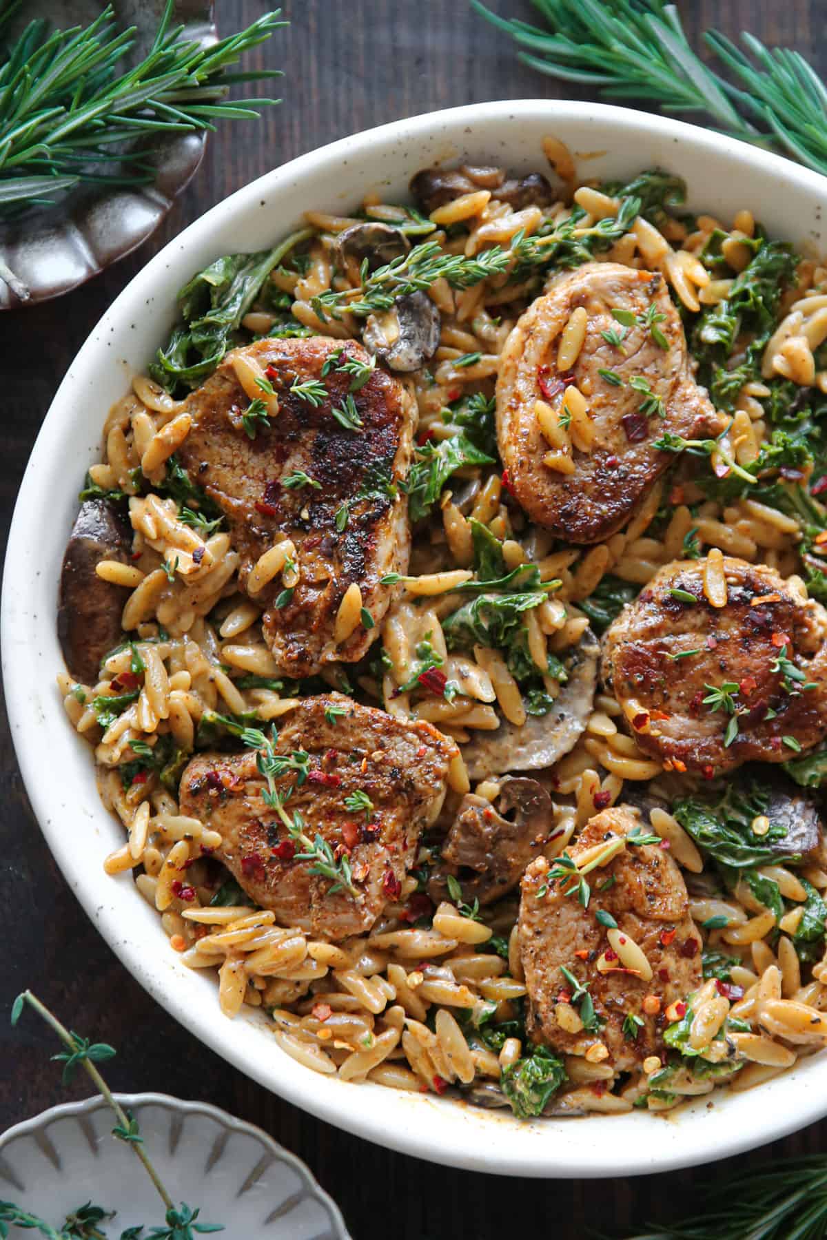 Creamy Pork Tenderloin Medallions with Orzo, Spinach, and Mushrooms - on a white plate.