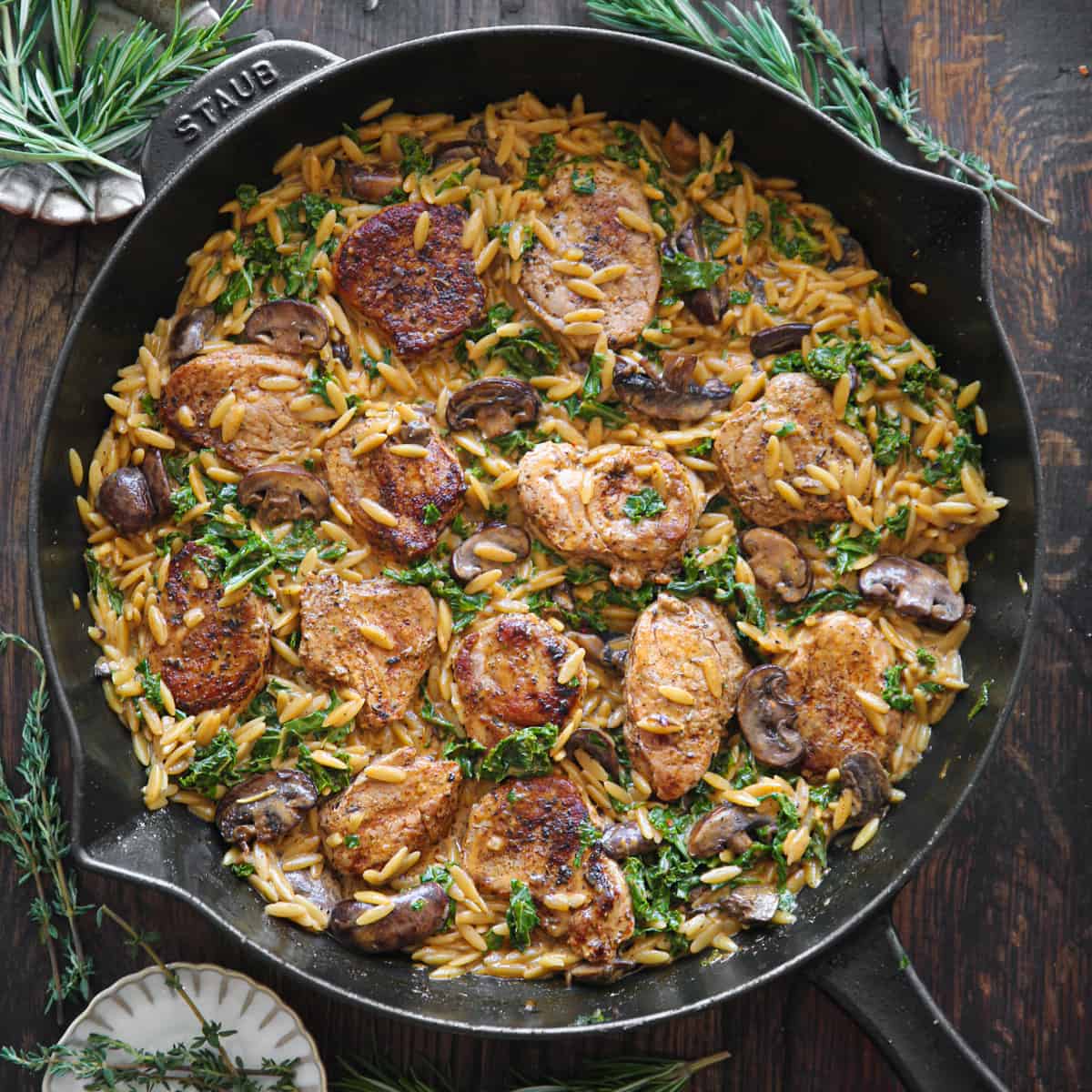 Creamy Pork Tenderloin Medallions with Orzo, Spinach, and Mushrooms - in a cast iron skillet.