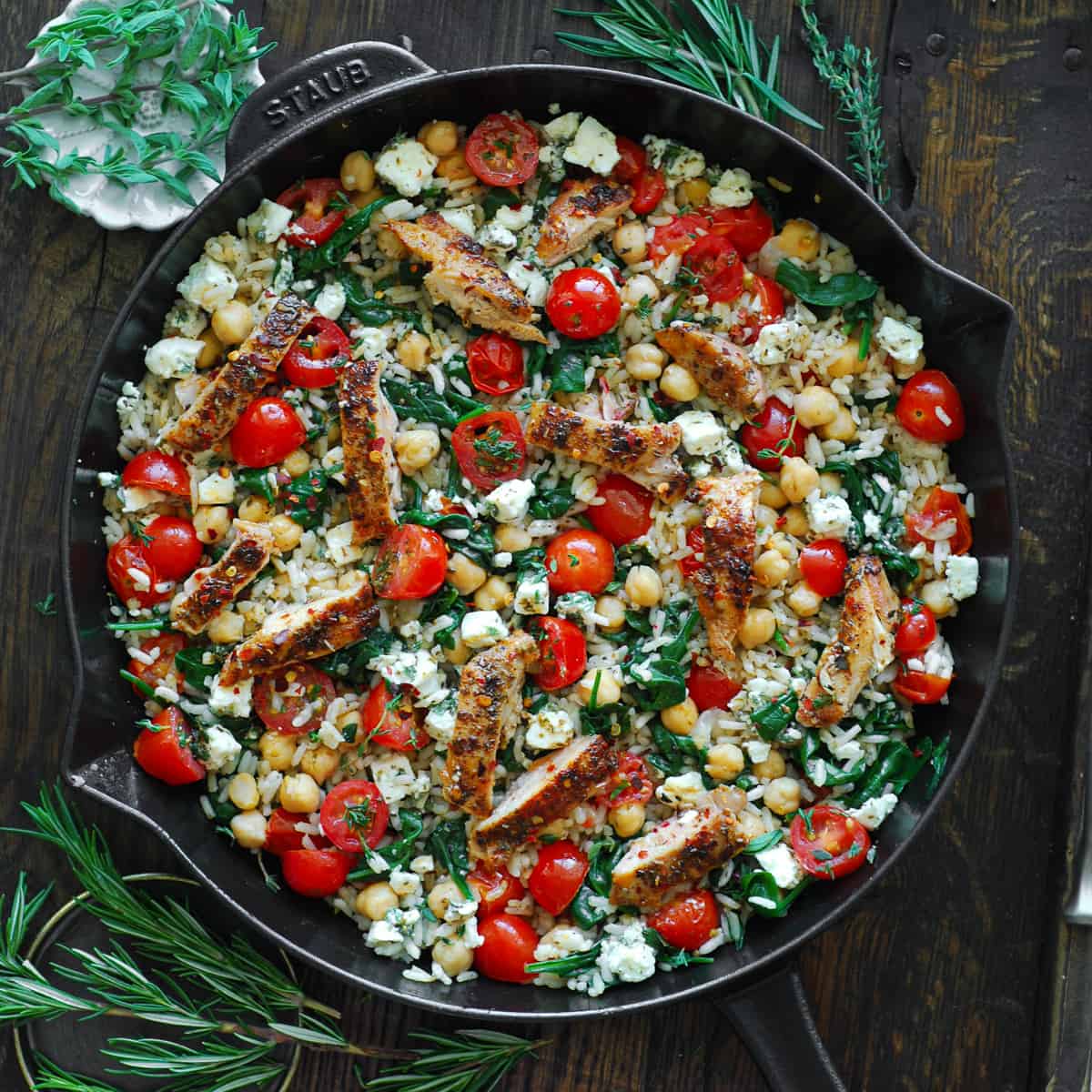 Greek Chicken and Lemon Rice with spinach, grape tomatoes, chickpeas, and feta cheese - in a cast iron skillet.